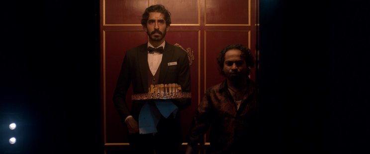 A Kölyök (Dev Patel) a bennfentes Alphonso (Pitobash) segítségével beszivárog az elit közé